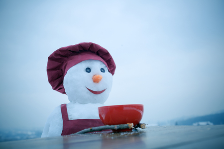 New year snowman in cook hat. Happy holiday celebration. Christmas food cooking. Snowman chef in winter with kitchen plate. Xmas or christmas cooking.の写真素材