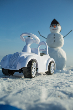 christmas snowman with toy car in pilot hat and glasses on blue sky, winter holiday celebration, new year and xmas, transport and travelの写真素材