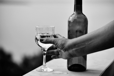 alcoholic beverage of white wine in green bottle and female hand taking glass outdoor on summer day on blue seaの写真素材