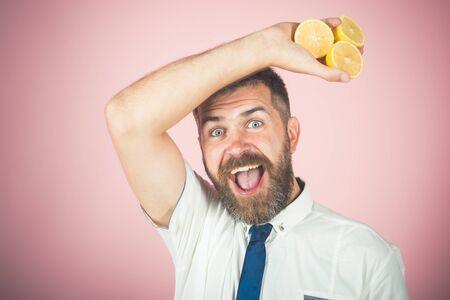 happy man with long beard hold lemon. Vitamin citrus at hipster on pink background. Vegetarian, health and wellbeing. Fruit and healthy organic food. Dieting and fitness.の写真素材