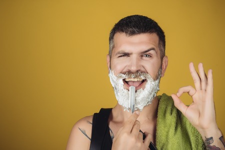 happy hipster in barbershop, new technology. Man cut beard and mustache with razor and shaving gel. Fashion and beauty, innovation. Barber and hairdresser. Haircut of bearded man, archaism.の写真素材