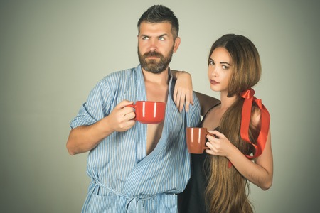 family of man and woman with red milk cup. man and girl with mulled wine on grey background. Refreshment and energy, break. Perfect morning with coffee. couple in love drink morning coffee or tea.の写真素材