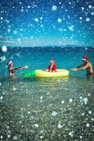 new year christmas snow concept Christmas happy family on pineapple mattress in water. New year man, girl with small boy. Santa child, parents at Christmas. Xmas party celebration, fathers and mothersの写真素材