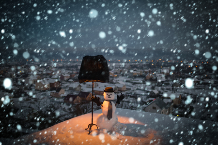 new year christmas snow concept Christmas or xmas decoration. Happy holiday and celebration. New year snowman from snow in hat, gloves and tie. Winter evening party. Snowman gentleman with black lamp.の写真素材