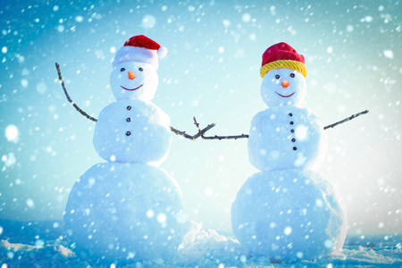 new year christmas snow concept Christmas or xmas decoration. Happy holiday and celebration. New year snowmen from snow in santa hat. Santa claus hat in winter. Snowman couple outdoor.の写真素材