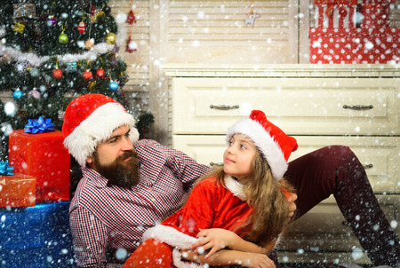christmas new year snow concept Christmas happy child and father with present box. New year small girl, man with gift. Santa kid, bearded man at Christmas tree. Xmas party celebration, fathers day.の写真素材