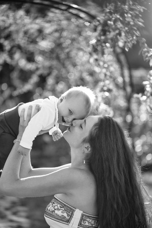 Happy cute baby boy, small, little, son, and pretty mother, woman, with long hair having fun, smiling, on sunny summer nature outdoors on natural background. Mothers day, family loveの写真素材