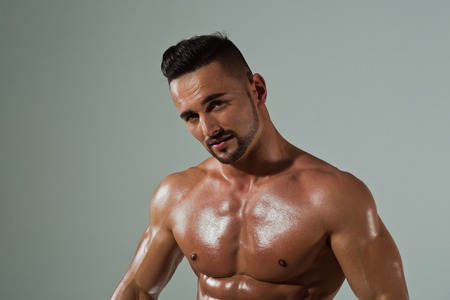 Athletic bodybuilder man on grey background. Coach sportsman with bare chest. Dieting and fitness. Man with muscular wet body and torso. Sport and workout.の写真素材