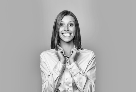 Pretty emotional girl or cute beautiful woman female model with red hair in white shirt smiles on blue backgroundの写真素材