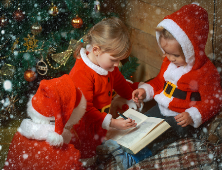 new year christmas snow concept Winter holiday and vacation. Xmas party celebration, childhood Christmas happy children in red hat. New year small girl and boy, happiness. Santa claus kidの写真素材