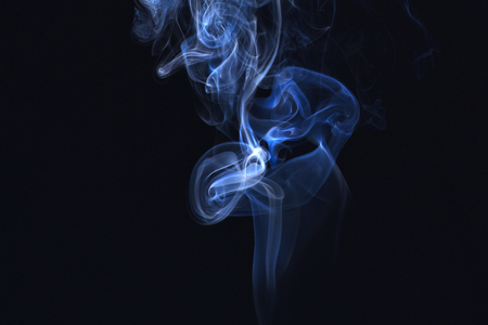 Blue ink in freeze motion, powder splatted explosion. Smoking cloud backdrop. Abstract background with smoke. Blue smoke on black background. Spirit and ghost, miracle.の写真素材
