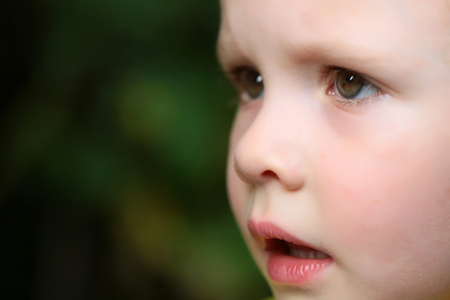 Face of cute baby girl or boy on blurred natural background. Child, childhood, family. Innocence, purity, infancy, future concept, copy spaceの写真素材