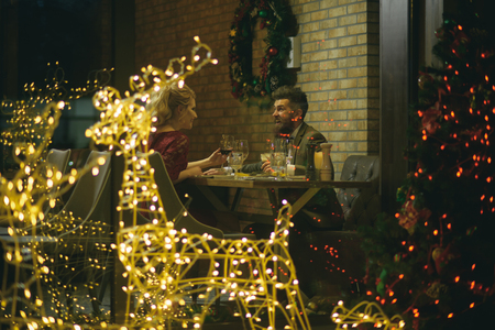 Happy family celebrate new year and christmas. Couple in love enjoy xmas cuisine, food, wine. Winter season romance. Woman and man in restaurant with festive decorations. Holidays celebration concept.の写真素材
