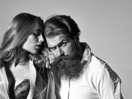 Young sensual couple of bearded handsome man with beard and pretty sexy girl or beautiful woman in red sexi bra on grey wallの写真素材
