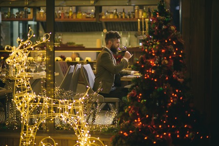 Man with long beard celebrate new year and christmas. Hipster enjoy wine in restaurant. Xmas party drinks, toast, alcohol. Winter holidays celebration concept.の写真素材