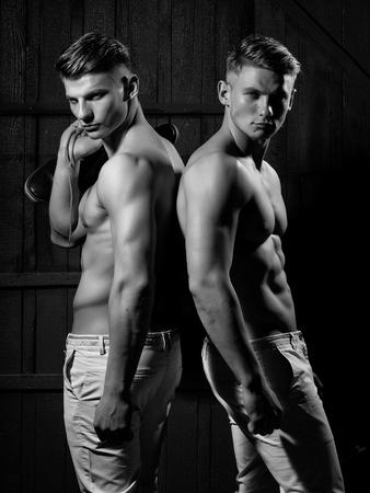 Two young male twins with sexy body showing their muscular torso and abs in studioの写真素材