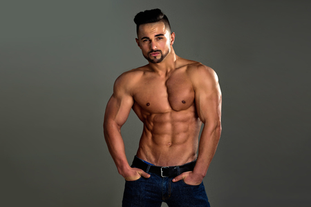 Coach sportsman with bare chest in jeans. Man with muscular body and torso. Athletic bodybuilder man on grey background. Sport and workout. Dieting and fitness.の写真素材