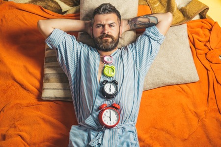 Relax and wake up, time. Man with clock in bedroom, loneliness. Tired hipster with clock. Bearded man sleep on floor with alarm clock. Time management, perfect morning.の写真素材