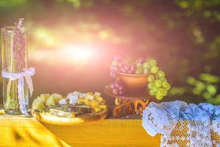 Still life of cheese plate, grapes and lavender in vase on sunny day on natural background. Food, appetizer, cuisine concept.の写真素材