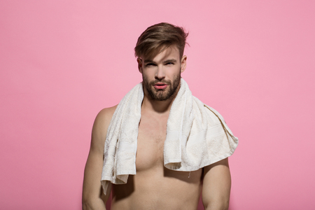 Man with bearded face, stylish hair, bath towel on muscular torso on pink background. Beauty, grooming, hygiene. Health, fitness, bodycare conceptの写真素材