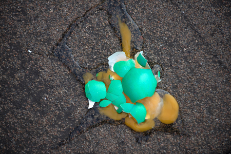 Easter egg broken on asphalt background. Green colored eggshell with yellow yolk. Fertility and rebirth concept. Spring holiday celebration. Easter tradition and symbol.の写真素材