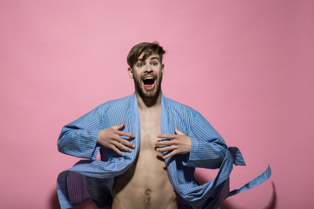 Happy macho with sexy torso in bathrobe. Man in blue dressing gown on pink background. Home clothes, leisure wear. Spa, wellness, grooming. Fashion, style concept.の写真素材