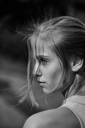 Pretty sexy cute young woman or girl with blonde hair in pink shirt and blue eyes with serious face , close upの写真素材