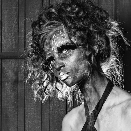 Woman with unusual paint make-up and curly hair in studioの写真素材