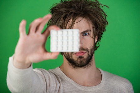 Drug and antidepressant, insomnia. Man with pills in blister pack. Health and medicine, hangover. Dieting pill and vitamin, man with anabolic. Cold, flu and headache treatment, hypnotic tablet.の写真素材
