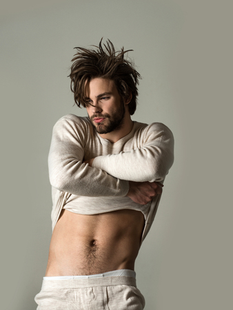 Insomnia, energy, single with uncombed hair. Sleepy man with beard on grey background. Barber and hairdresser, male fashion. Man with disheveled hair in underwear. Morning wake up, everyday life.の写真素材