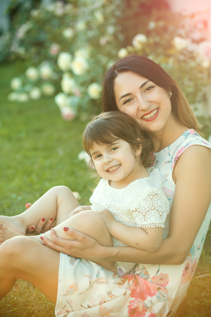 Woman smiling with child in summer garden on floral environment. Happy childhood and parenting. Mothers day concept.の写真素材