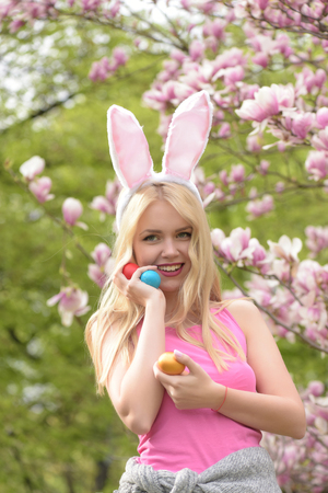 easter woman with eggs in bunny ears at magnolia, Spring. Easter. Holidays, celebrationの写真素材