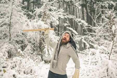skincare and beard care in winter, beard warm in winter. Camping, traveling and winter rest. Temperature, freezing, cold snap, snowfall. Man lumberjack with ax. Bearded man with axe in snowy forest.の写真素材