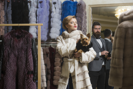 Fashion and beauty, winter. Couple in love among fur coat with dog, luxury. Date, couple, love, man and woman. Purchase, business, moneybags. Woman in fur coat with man, shopping, seller and customer.の写真素材