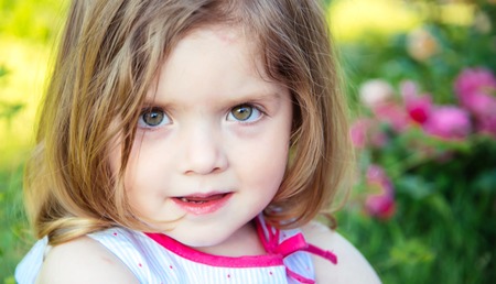 Child girl with brown eyes on cute face on sunny summer day on floral environment. Innocence and future concept.の写真素材