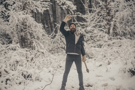 Man lumberjack with ax. Bearded man with axe in snowy forest. Temperature, freezing, cold snap, snowfall. skincare and beard care in winter, beard warm in winter. Camping, traveling and winter rest.の写真素材
