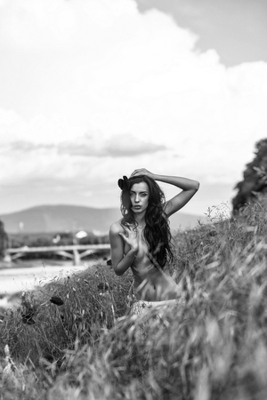 young sexy naked woman with pretty face and long brunette hair has bare slim body with chest and belly in green field with red poppy flowers outdoorの写真素材