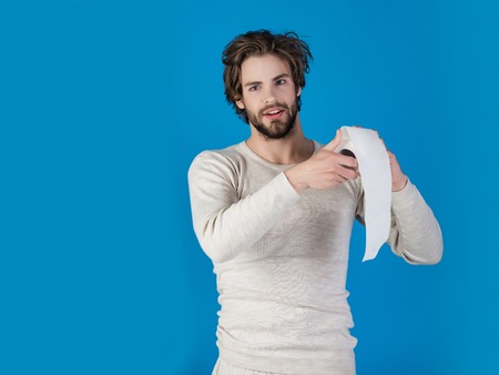 Sterility and purity. Man with happy face hold toilet paper, single. Hygiene and sanitary. Man in underwear with disheveled hair, morning. WC and restroom. diarrheaの写真素材