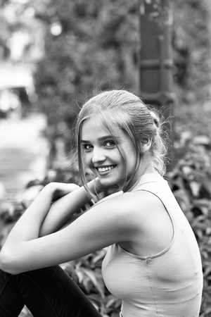 Pretty sexy young woman or girl with tied in bun blonde hair in pink shirt with cute face smiling on natural backgroundの写真素材