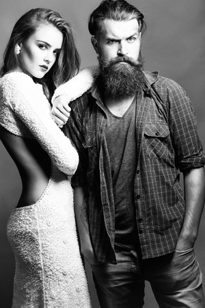 young couple of pretty cute girl beautiful woman with long brunette hair in white fashionable dress and bearded handsome man on grey backgroundの写真素材