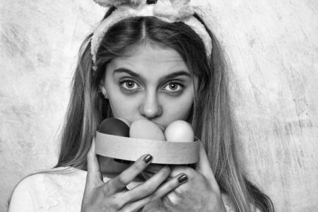 happy easter girl in pink bunny ears with colorful painted eggs in box, has long blonde hair and...