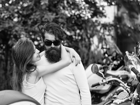 Young couple of bearded hipster man and beautiful girl hug in love outdoor near motor bikeの写真素材