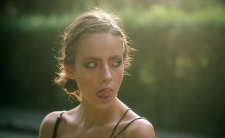 Young woman show tongue on makeup face, beauty. Girl with stylish brunette hair, hairstyle on...