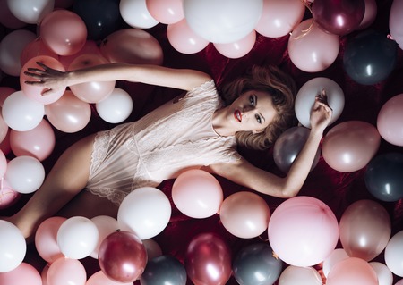 Beauty and fashion, cosmetics, vintage. Pin up woman in balloons, round pot blush. Retro woman with party balloons, celebration. Vintage, birthday, look. Sexy girl with retro makeup and blond hair.の写真素材