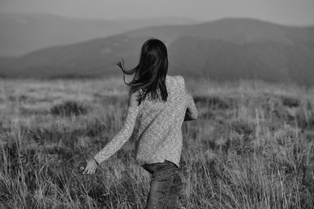 Pretty young cute sexy woman or girl in jeans and sweater outdoors on grass field and foggy grey sky outdoorの写真素材