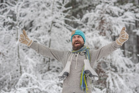 Winter sport and rest, Christmas. Bearded man with skates in snowy forest. Man in thermal jacket, beard warm in winter. skincare and beard care in winter. Temperature, freezing, cold snap, snowfall.の写真素材
