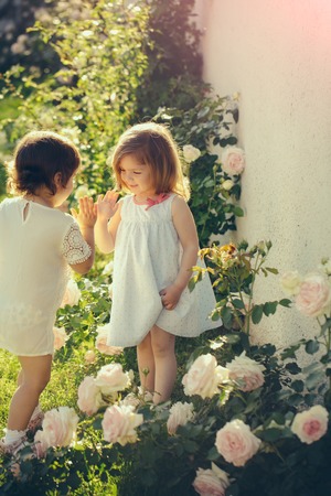 Children playing patty cake in summer garden on sunny day.の写真素材