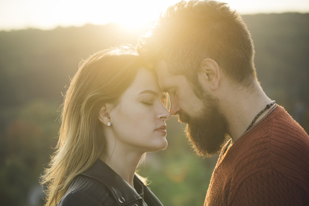 Couple with pensive faces stand close, closed eyes. Love and romantic concept. Couple in love going to kiss, defocused background, sunny autumn day. Man with beard and woman happy together.の写真素材