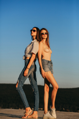Sexy girlfriends in shirt and topless, breast, on blue sky. Love, romance, affection. Friends, partners, lovers, relations. Lgbt, lesbian, bisexuality, transgender, gender. Equality, rights, freedom.の写真素材