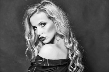 Closeup view of one attractive blonde woman with long curly hair in checkered shirtの写真素材